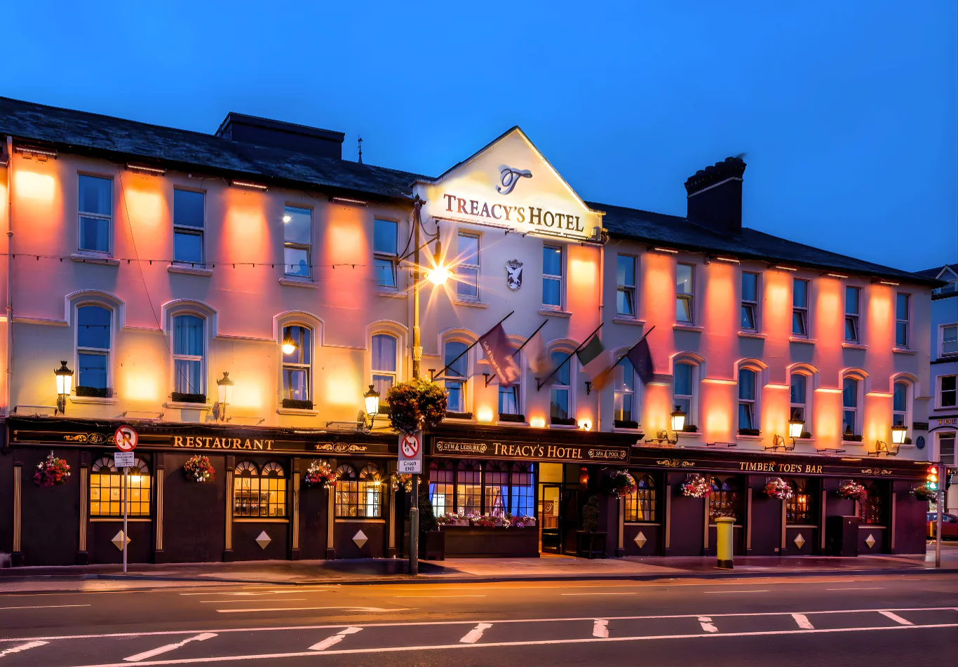 Welcoming Treacy's Hotel facade at dusk, warm lights, inviting bar and restaurant await guests on a charming street.