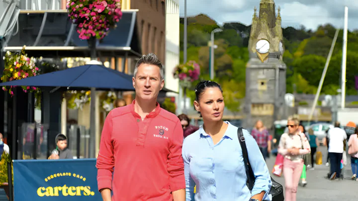 Guests explore vibrant city street with lively cafes and historic architecture, ideal for a cultural getaway.