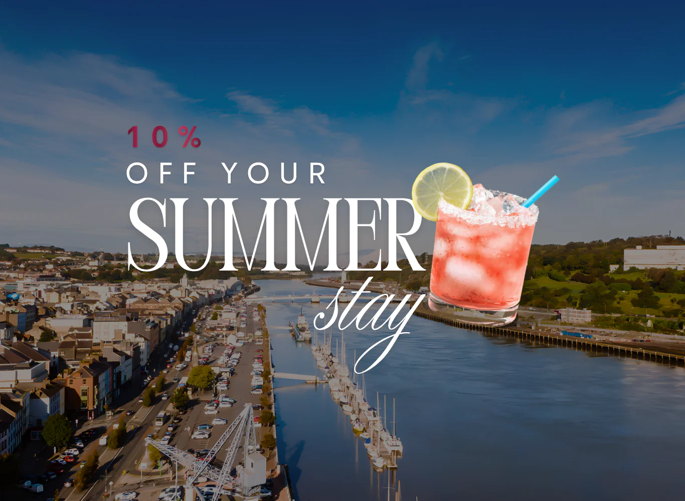 Charming riverside town view with summer drink and 10% off stay offer. Perfect for a relaxing holiday getaway.