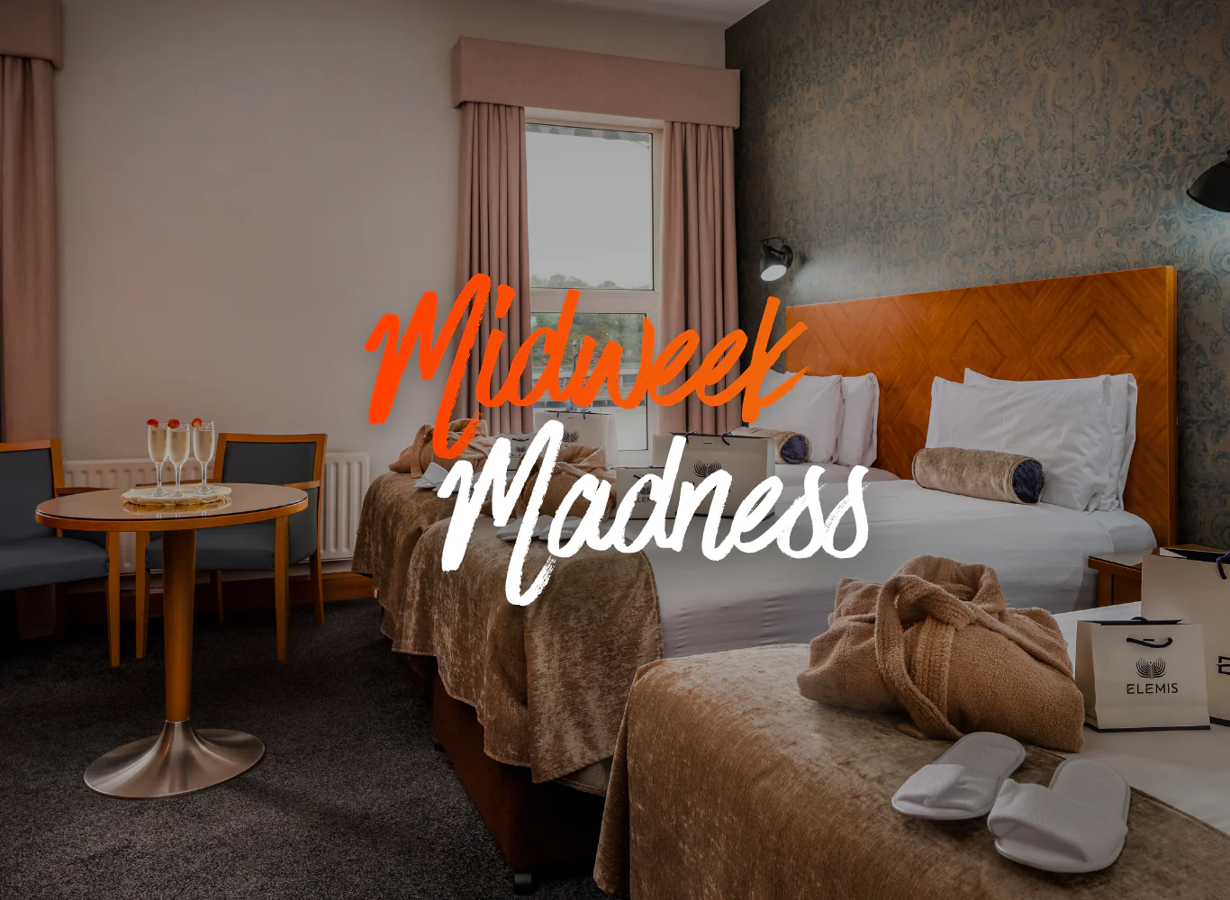 Elegant hotel room with twin beds, Elemis spa gift, and table set for two near window; perfect for a relaxing stay.