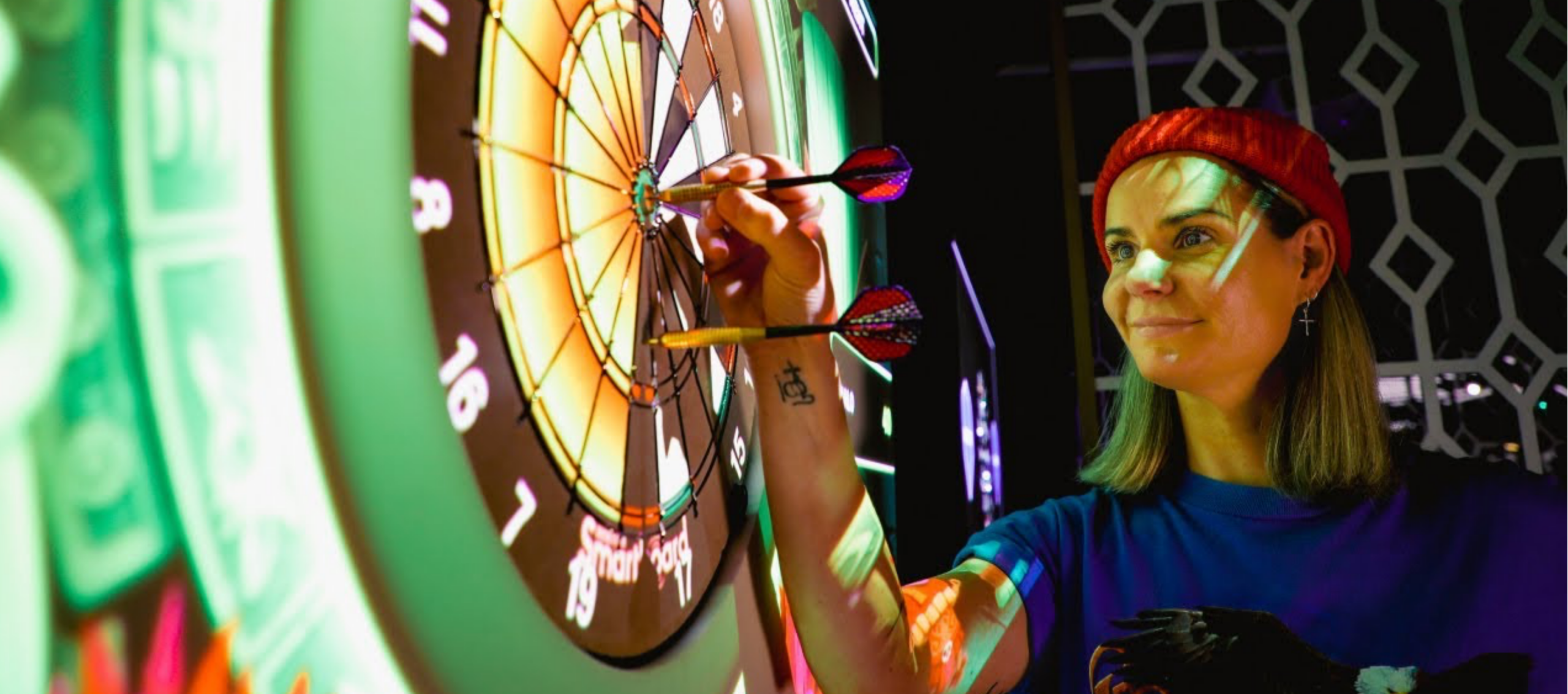 Guest enjoying darts in the vibrant games room, featuring colourful lighting at our welcoming hotel.
