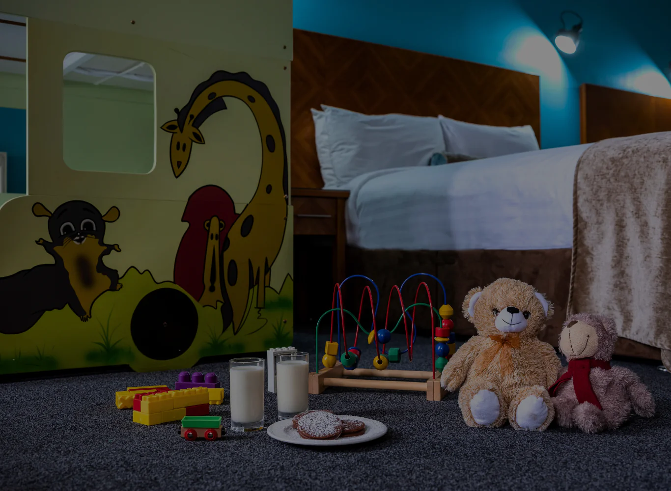Cosy family hotel room with bunk beds, soft toys, milk, and cookies, perfect for children, offering a welcoming stay.