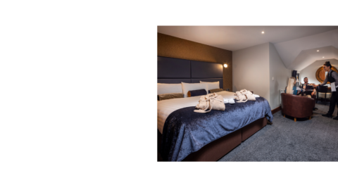 Elegant hotel room with plush king-size bed, luxurious linens, cosy seating area, and warm ambient lighting. Perfect for relaxation.