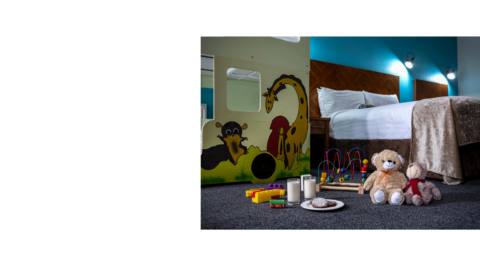 Family-friendly hotel room with cosy bed, playful animal wall art, toys, teddy bears, milk, and biscuits for a welcoming stay.