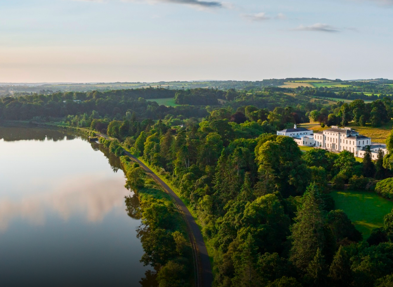 Luxurious hotel nestled amid lush greenery beside a serene river, offering tranquil countryside views for a relaxing getaway.