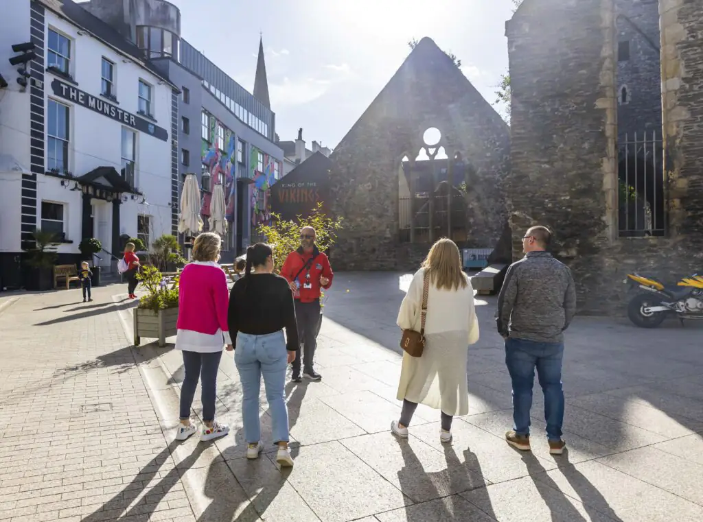 Viking Triangle Walking Tour Guests enjoy sunny courtyard beside The Munster, exploring historical architecture and vibrant surroundings.