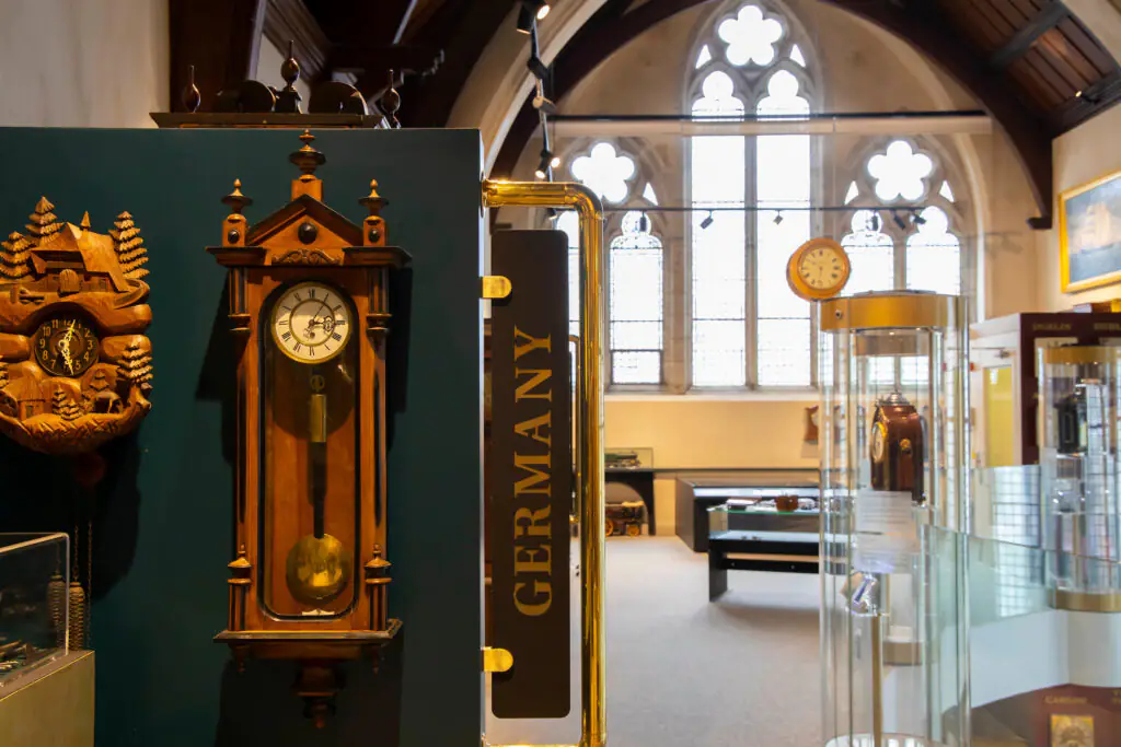 Museum of Time Guests explore a charming historic museum room with vintage clocks, stained glass windows, and classic wooden décor.