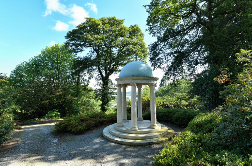 Mount Congreve Gardens Waterford Serene garden view with elegant white gazebo under blue sky, lush greenery surrounds enchanting path. Perfect for relaxation.